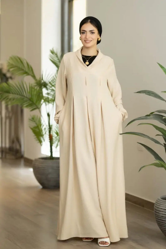 Beige maxi dress with pleated front and elastic sleeves, made from Ketan fabric.