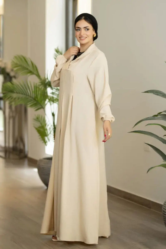 Beige maxi dress with pleated front and long sleeves, made from Ketan fabric.